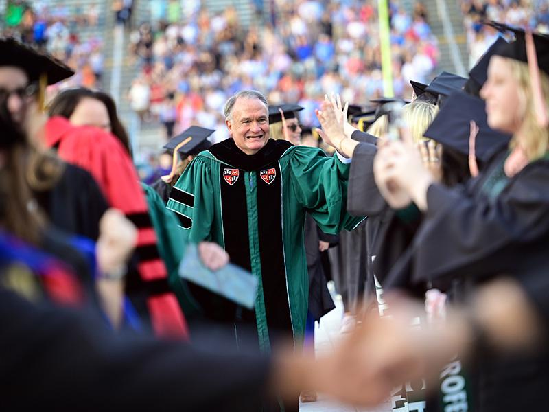 President Michael Fitts high-fives graduates as heads to the stage.