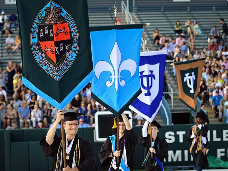 Graduates process into the stadium carrying the ceremonial gonfalons. 