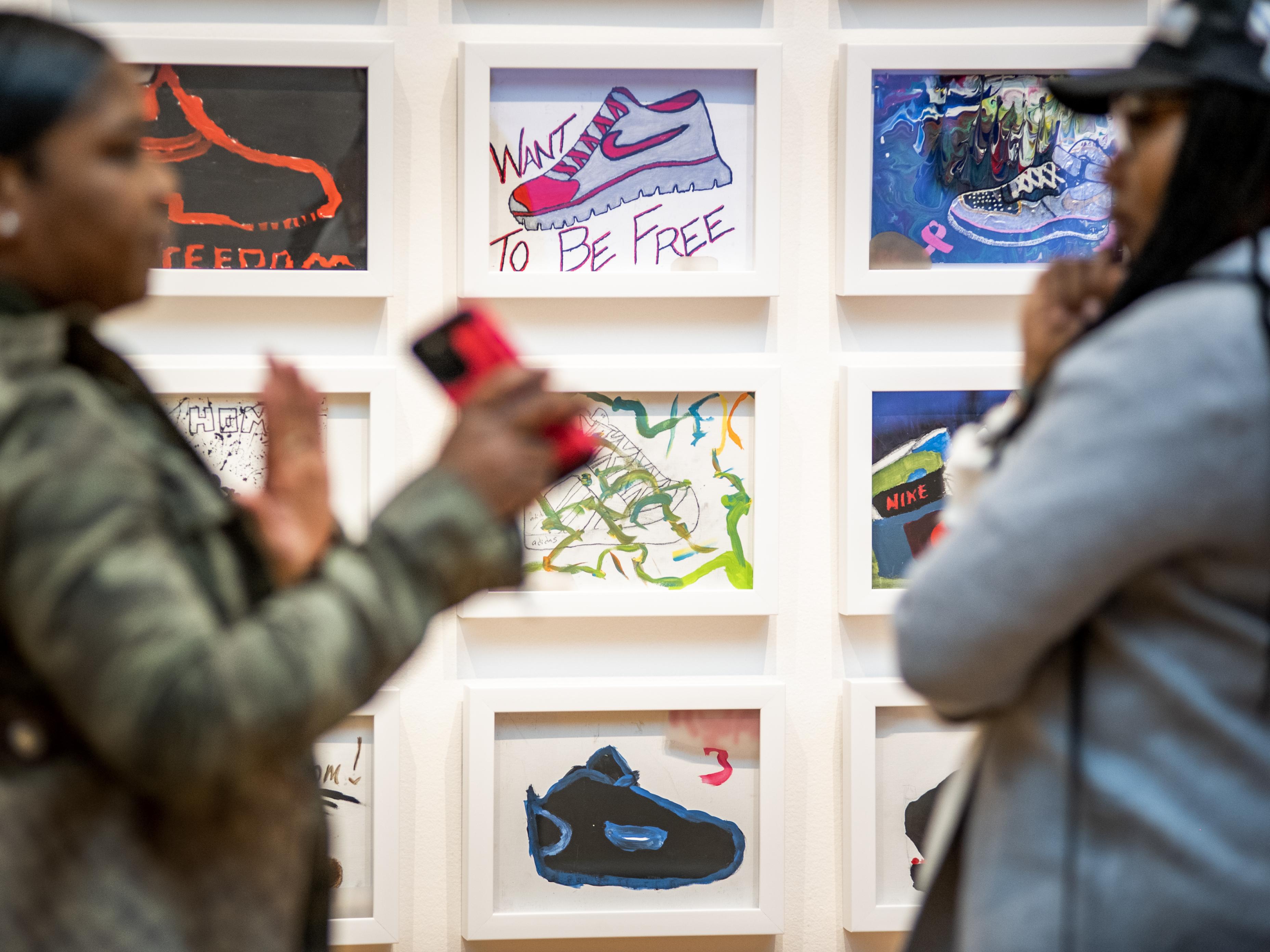 Visitors chat near a display of Steps to Freedom, paintings created by anonymous youth in a creative expression workshop led by artist and activist Sheila Phipps at the Travis Hill School located in New Orleans’ juvenile detention center and adult jail