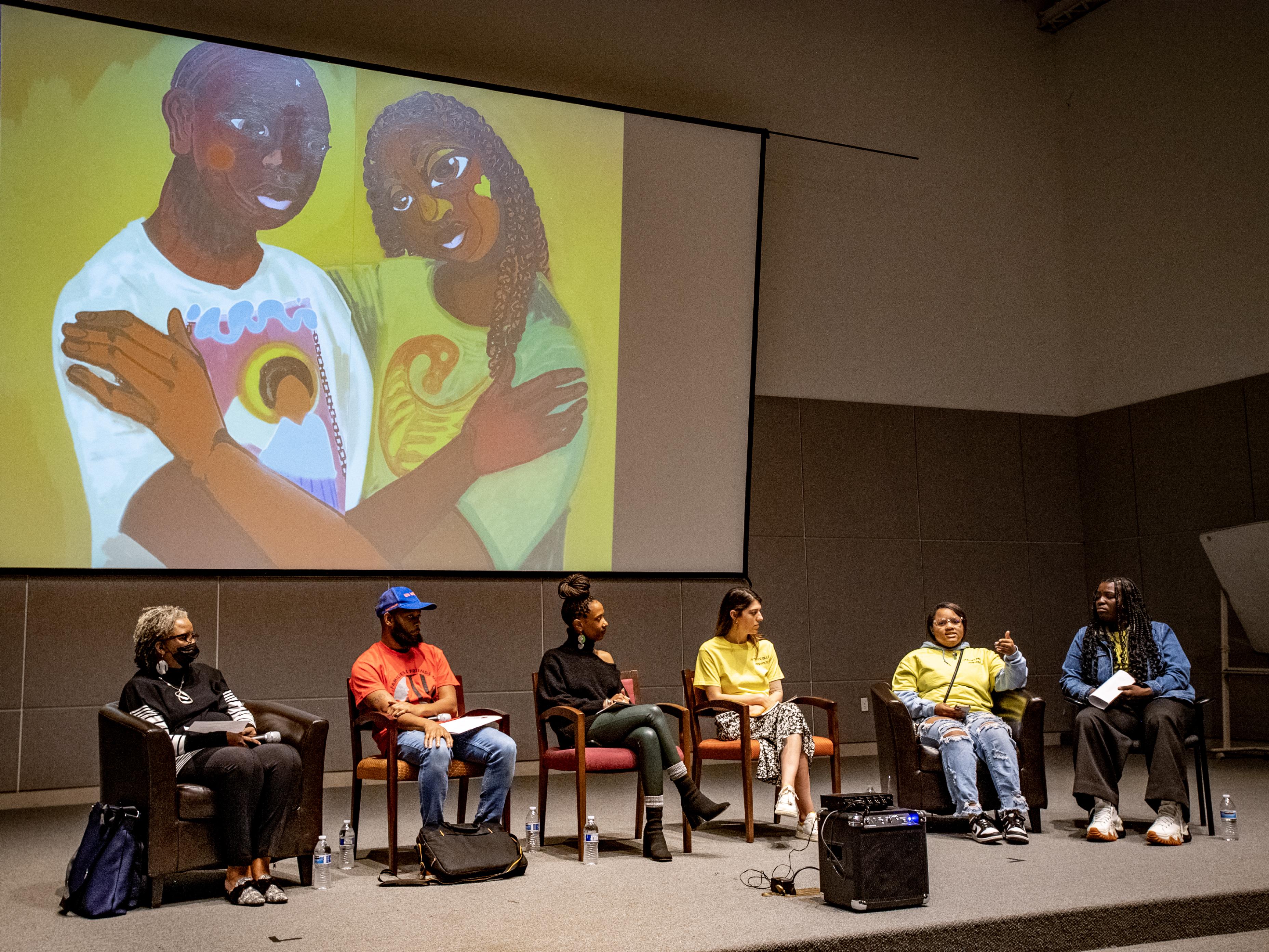 Panelists discuss the current juvenile justice crisis and how the exhibition came to be. A detailed image of ‘Together, Towards Freedom,’ a mural in the exhibit created by Langston Allston and youth from the Young Artist Movement, serves as the backdrop.