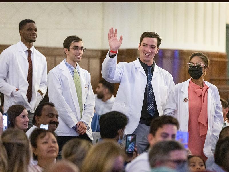 A student waves to their loved ones in the audience. 