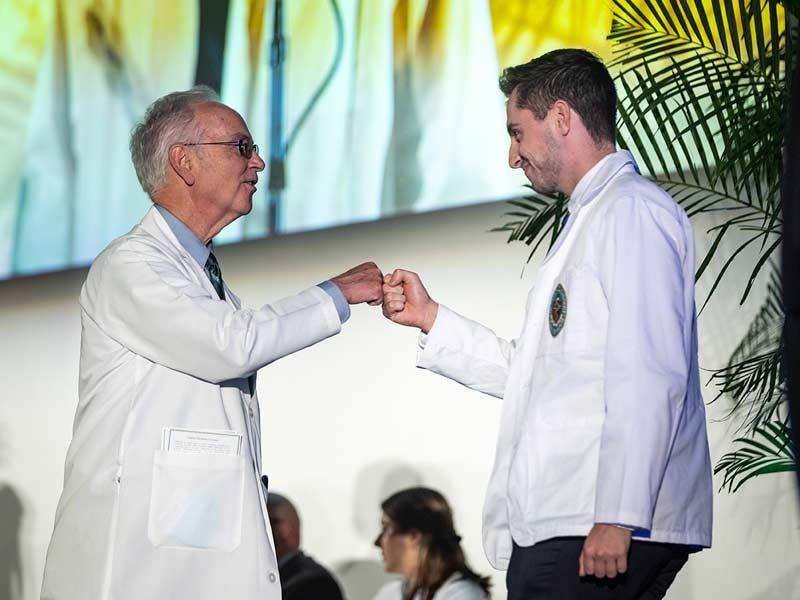 A student fist bumps School of Medicine Dean Lee Hamm as they go across the stage. 