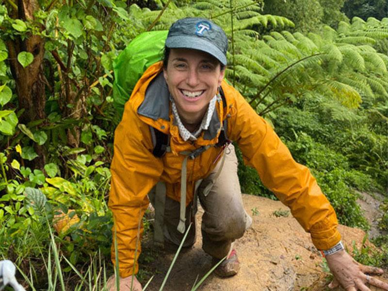 Nicole Gasparini poses for photo on large rock in forest