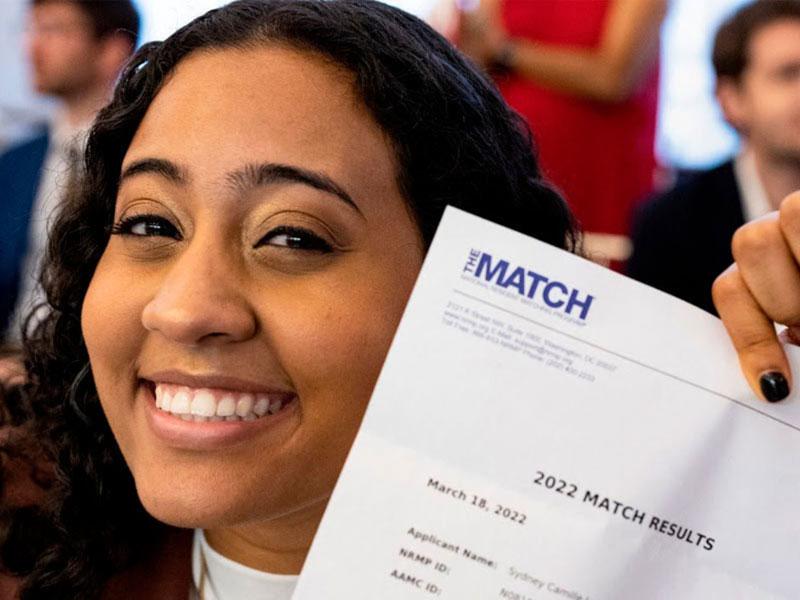 Student smiling and holding her Match day letter Student smiling and holding her Match day letter