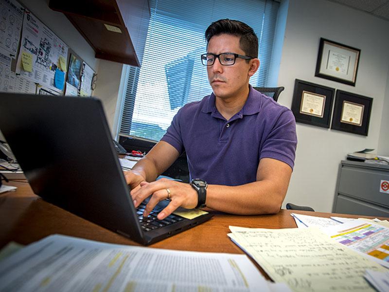 Nicholas Sandoval works from laptop in office Nicholas Sandoval works from laptop in office