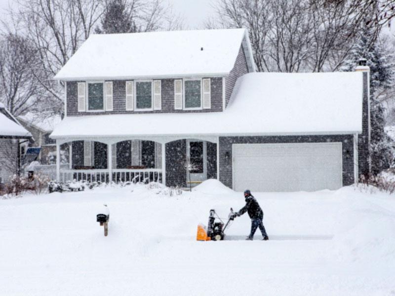 Man plowing snow in front of his home during winter storm