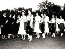 A procession of Newcomb College juniors makes their way past the senior class for the start of theMay Day celebration on Newcomb Quad in 1953.