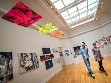 Professors take a stroll through an exhibition of student work in the Carroll Gallery.