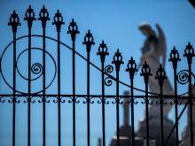 A detailed wrought iron gate guards the entrance to a cemetery in the Upper 9th Ward.