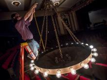 The chandeliers in Dixon Hall get a once over before the Summer Lyric Theatre season begins. 