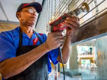 Nathaniel Robinson, a utilities specialist with Sodexo, buffs the Lavin-Bernick Center food court’s metal door to make it “look like new” in preparation for its re-opening on August 15th.