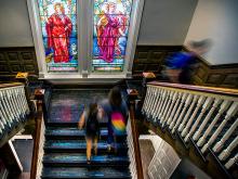 Figures in Tiffany windows keep a watchful eye over the stairs in in Tilton Memorial Hall. 