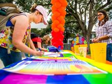 Students decorate a banner with positive messages for the start of Pride Month at Tulane.