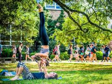 Leslie Dingeldein, a PhD student in French and her partner Bryson Lloyd practice acroyoga on the Johnston Quad for an attentive audience.