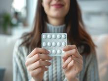 A woman holds a packet of pills