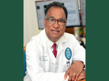 Portrait of a smiling doctor in a white lab coat and glasses.