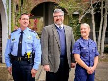 Graduates Lieutenant Mark Mulla (left) of the New Orleans Police Department and Lieutenant Marina Turner (right) from the United States Coast Guard stand with Michael Wallace (center), director of Tulane’s Emergency and Security Studies. (Photo by Jennife