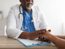 A doctor holds a patient's hand