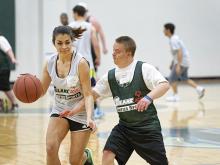 Julie Bartens, left, drives to the basket as Special Olympics athlete Aaron Rhode plays defense
