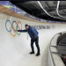 Jared Firestone touches Olympic rings on a curved ice bobsled track.
