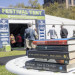 Stack of books on a white table, a festival tent and people in the background.
