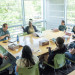 Group of people having a discussion around a table in a bright room.