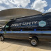 Black Tulane University Public Safety mobile unit van with blue lights, parked near a dome stadium.