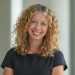 Headshot of a smiling woman with curly blonde hair.