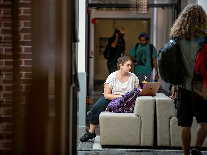 In the bustling lobby of the Dixon Performing Arts Center, second-year graduate student Sarah Campbell focuses on a reading for Music, Religion & Spirit class.